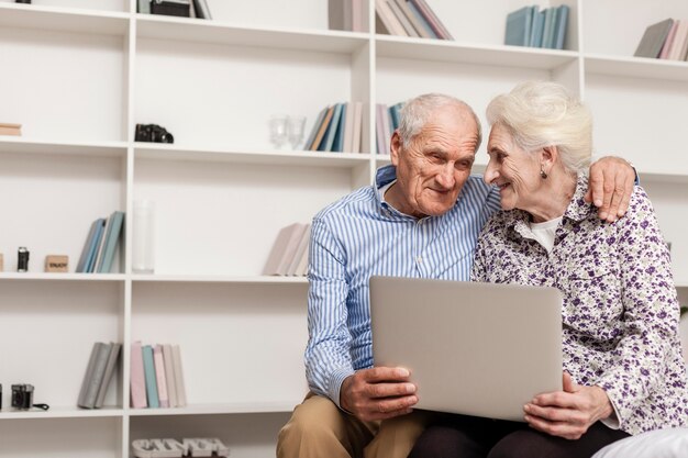 Reizende ältere Paare, die einen Laptop anhalten
