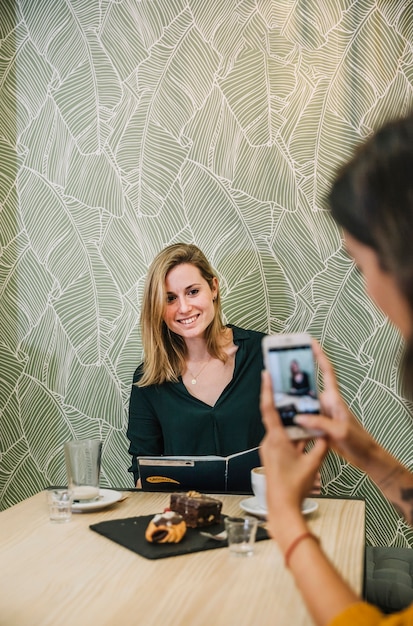 Reizende Frau, die für Foto im Café aufwirft