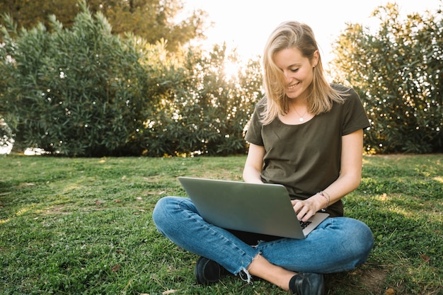 Reizende Frau, die Laptop auf dem Boden verwendet