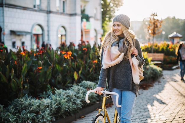 Reizende Frau, die mit Fahrrad im Park geht