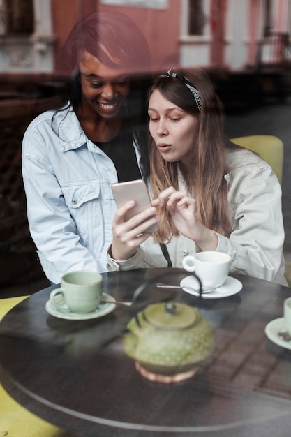 Reizende Frauen, die Handy betrachten