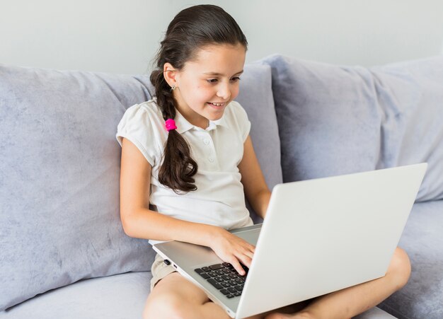 Reizende kleine Mädchen, die ihren Laptop verwenden