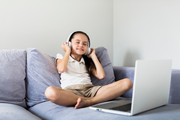 Reizende kleine Mädchen, die ihren Laptop verwenden