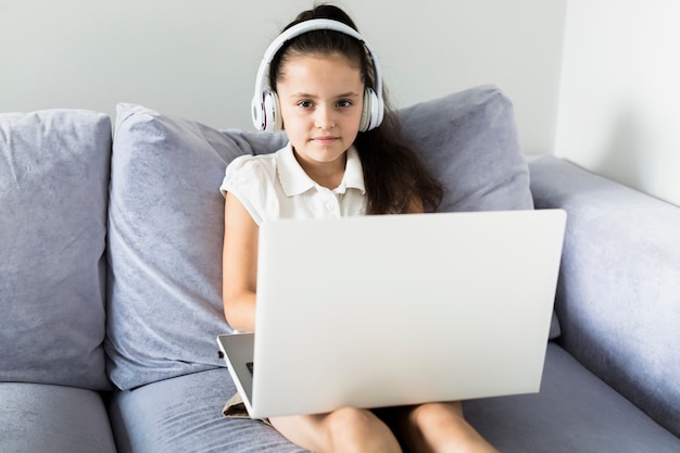 Reizende kleine Mädchen, die ihren Laptop verwenden