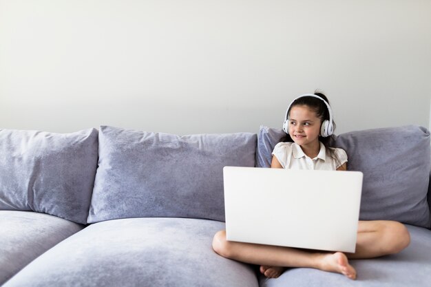 Reizende kleine Mädchen, die ihren Laptop verwenden