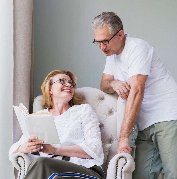 Reizender älterer Mann und Frau, die auf einem Sofa lächelt