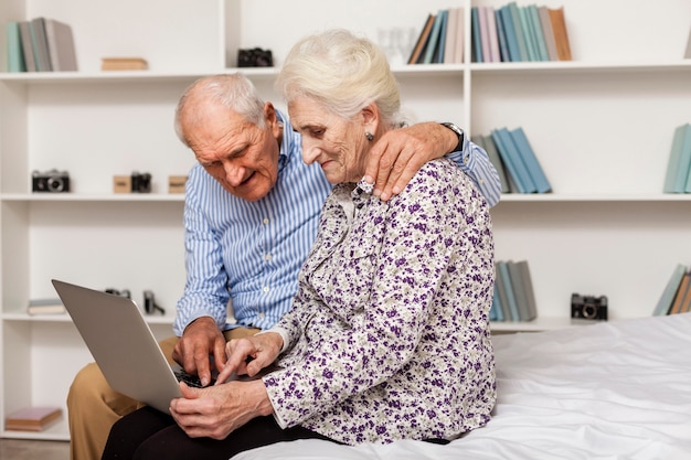 Reizender älterer Mann und Frau, die einen Laptop verwendet