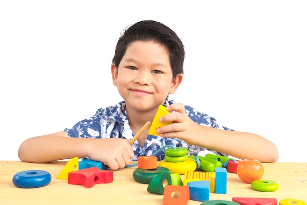 Reizender asiatischer Junge ist buntes hölzernes Blockspielzeug des Spiels