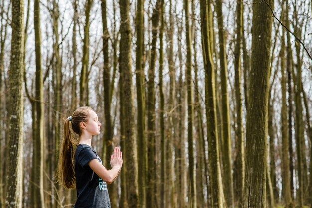 Reizender Jugendlicher, der Yoga unter Bäumen tut