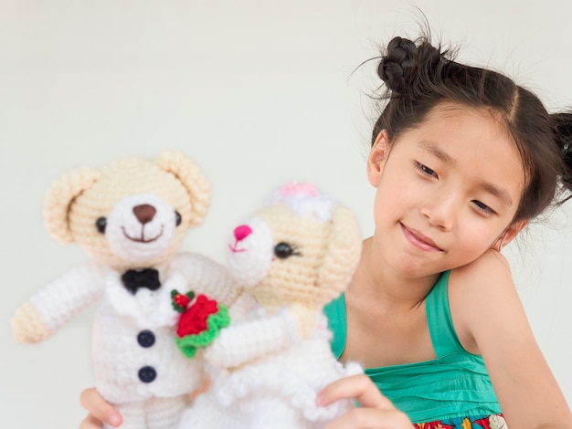 Reizendes asiatisches Kind spielt Hochzeitsbärnpuppen