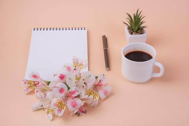 Reizendes Blumenkonzept mit Notizbuch und Kaffeetasse