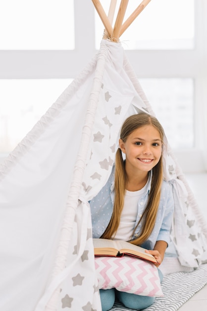 Kostenloses Foto reizendes glückliches mädchen, das mit einem buch aufwirft