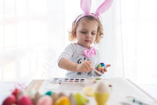 Reizendes Mädchen, das Eier für Ostern verziert