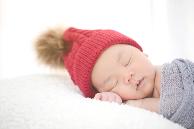 Reizendes neugeborenes asiatisches Baby, das auf pelzigem Stoff schläft