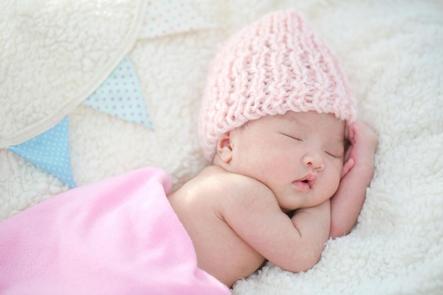 Reizendes neugeborenes asiatisches Baby, das auf pelziger Decke schläft