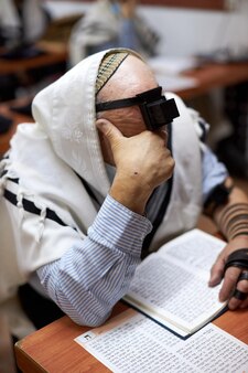 Religiöser jude mit tefillin auf der stirn und einem tallit auf dem kopf, der ein hochwertiges foto betet