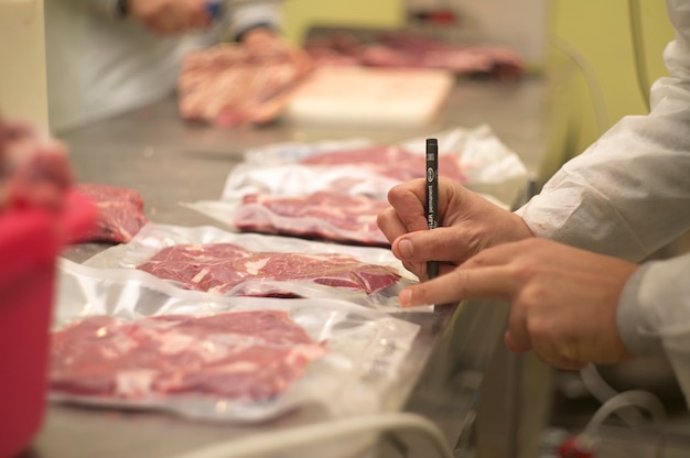 Reparto di una macelleria in cui vengono tagliati und pezzi di carne per poi essere messi dentro a buster di plastica per essere conservata sottovuoto.