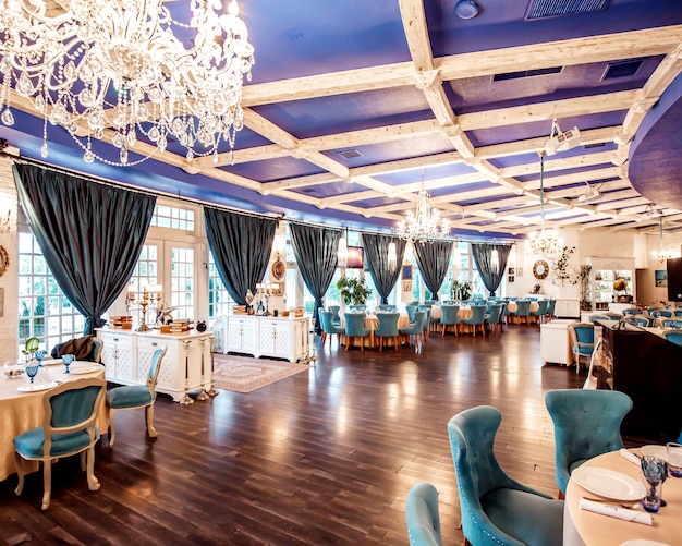 Restauranthalle mit türkisfarbenen Stühlen, dunkelblauen Fenstern mit französischen Fenstern