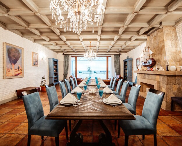Restauranttisch für 12 Personen mit blauen Stühlen, Kamin, weißen Backsteinmauern und breitem Fenster