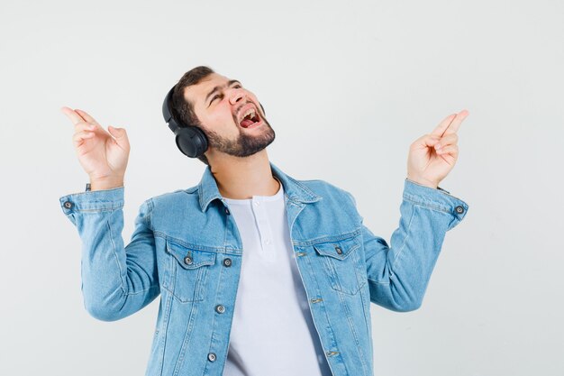 Retro-Art Mann, der Musik mit Kopfhörern in Jacke, T-Shirt hört und amüsiert, Vorderansicht schaut.