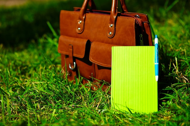 Kostenloses Foto retro braune mann ledertasche und notizbuch im hellen bunten sommergras im park