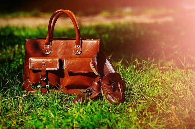 Retro braune Schuhe und Mann Ledertasche im hellen bunten Sommergras im Park