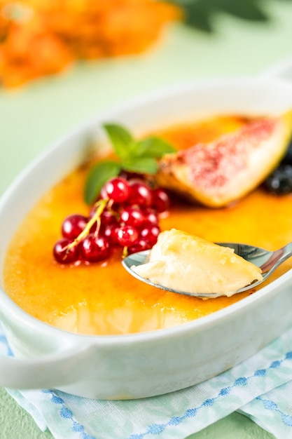 Rezept für Creme Brulee Dessert mit frischen Feigen, Blaubeeren und Johannisbeeren auf einem grünen Steintisch in Herbstkomposition.