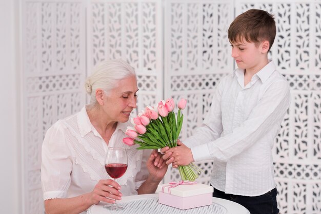 Riechende Tulpenblumen der älteren Frau gegeben von ihrem Enkelkind