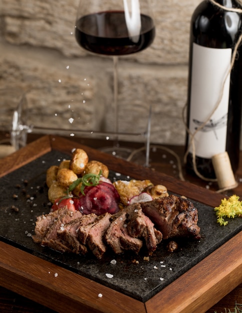 Rindersteak mit Salzkartoffeln und Kräutern und einem Glas Rotwein fein schneiden