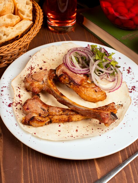 Rindfleisch, Lammkarreekebab diente mit Zwiebelscheiben, Gemüse und Kräutern, Lavash in der weißen Platte.