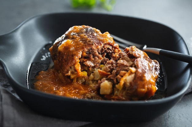 Rindfleischeintopfkugel mit Gemüsegefühl in Soße auf dunklem Teller. Nahansicht