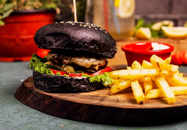 Kostenloses Foto rindfleischkäseburger der schwarzen schokoladenwanne mit gemüseschnellimbiß, pommes-frites und ketschup.