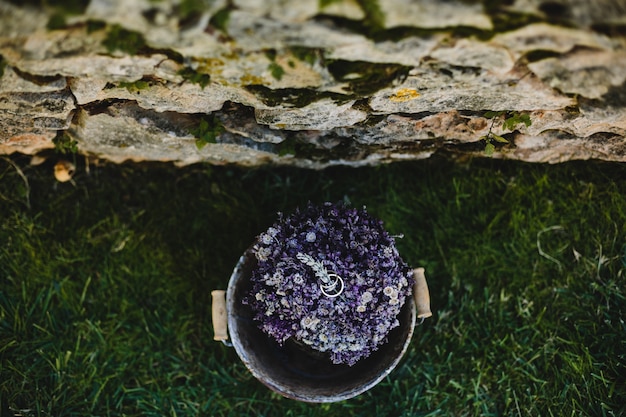 Ringe der goldenen Hochzeit liegen auf dem Blumenstrauß des violetten lavander