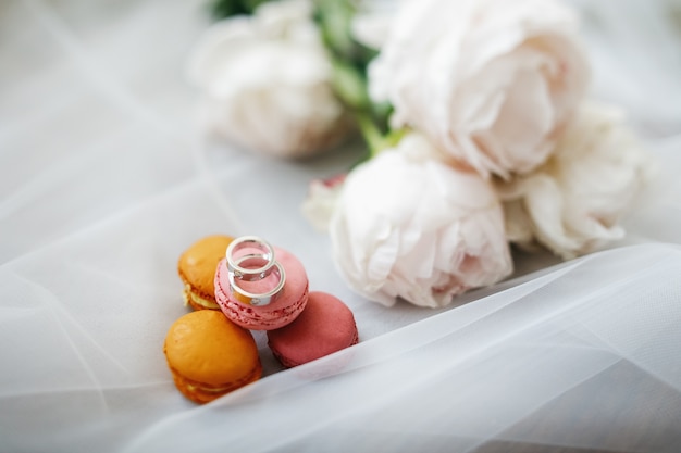 Ringe der silbernen Hochzeit liegen durch weißen Blumenstrauß auf dem Boden