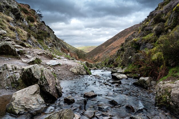 Rocky River fließt durch Berge mit dunklen Wolken