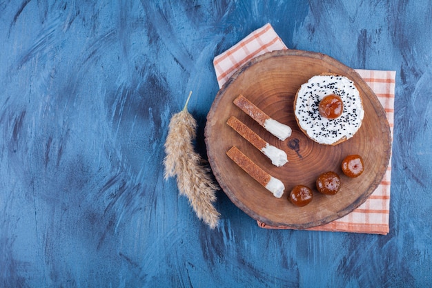 Roggentoastbrot mit Sauerrahm und Beerenmarmelade auf Holzstück.