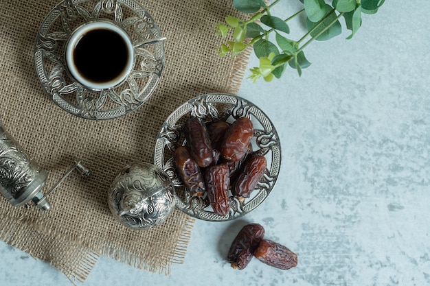 Rohe bio-datteln auf glasuntertasse mit tasse kaffee.