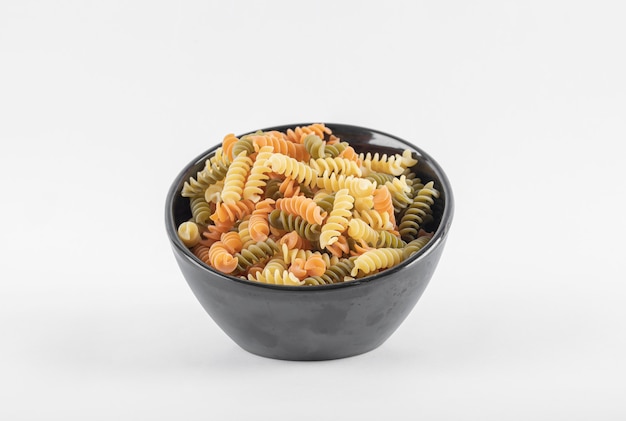 Rohe bunte Fusilli-Nudeln in der dunklen Schüssel.