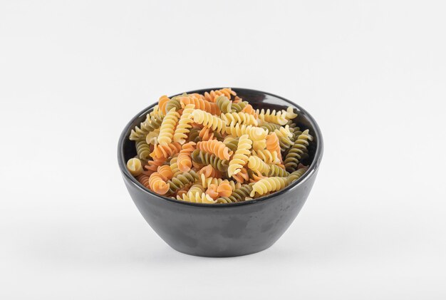 Rohe bunte Fusilli-Nudeln in der dunklen Schüssel.