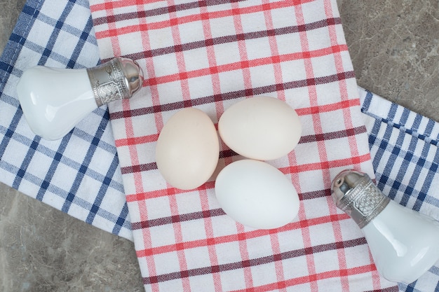 Rohe Eier und Gewürze mit Tischdecke auf Marmoroberfläche. Hochwertiges Foto