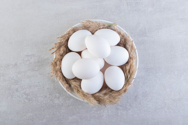 Rohe frische weiße Hühnereier, die auf eine Steinoberfläche gelegt werden.