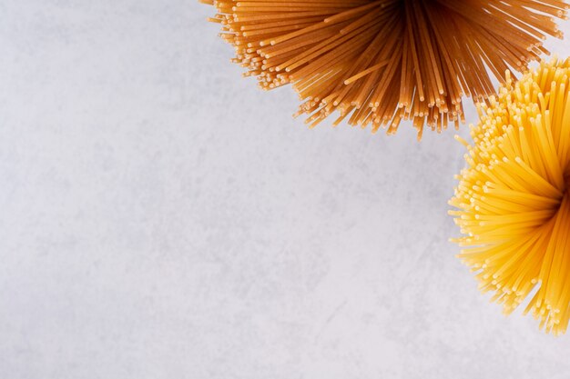 Rohe gelbe und braune Spaghetti auf weißer Oberfläche