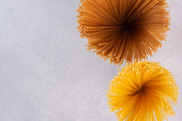Rohe gelbe und braune Spaghetti auf weißer Oberfläche
