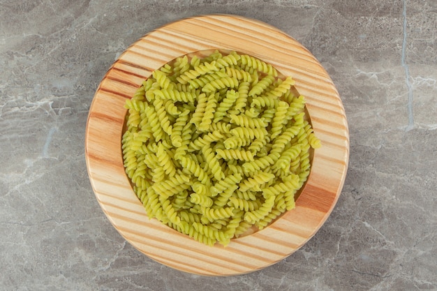 Rohe grüne Fusilli auf Holzplatte