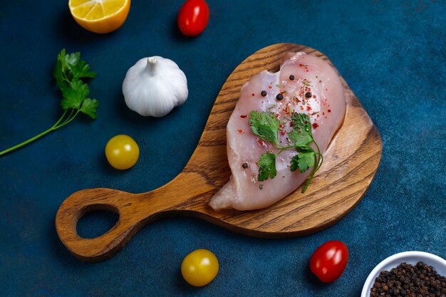 Rohe Hähnchenbrustfilets auf hölzernem Schneidebrett mit Kräutern und Gewürzen Beschneidungspfad eingeschlossen