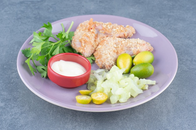 Rohe Hühnerflügelnuggets auf lila Platte.