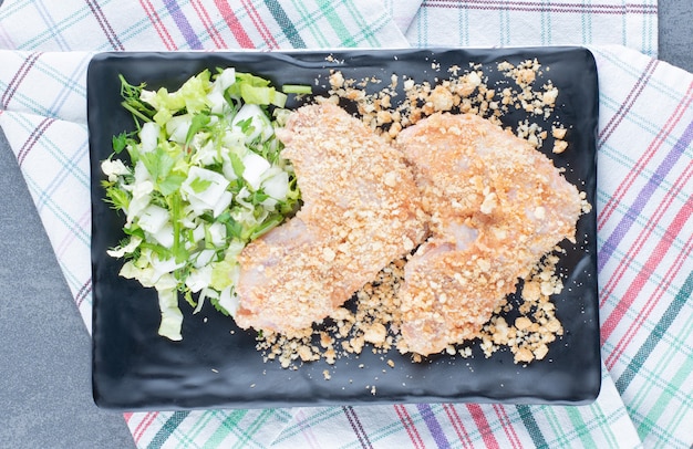 Rohe Hühnerflügelnuggets auf schwarzem Teller.