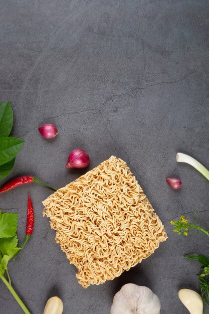 Rohe Instant-Nudel bereit zu kochen Isolat mit Zutat der heißen und sauren Suppe auf schwarzer Wand.