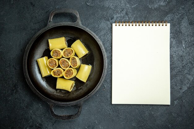 Rohe italienische Nudeln der Draufsicht mit Fleisch innerhalb der Pfanne auf dem dunklen Hintergrundnudelteigmehlfutter