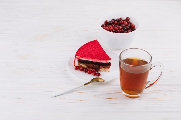 Rohe organische Beeren der roten Johannisbeere und Kuchenscheiben mit Kräuterteeschale